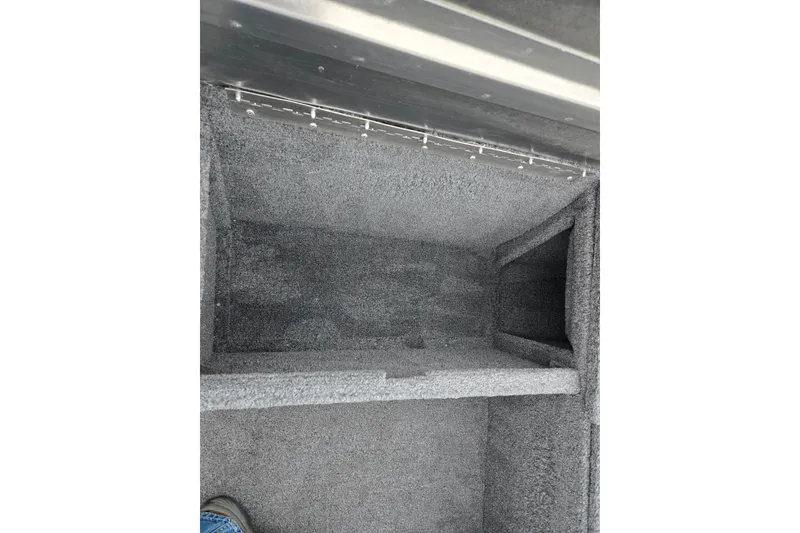 Slide: The Image of Interior storage compartment of 2025 Tracker Pro 170 boat, featuring gray carpeting. - 14
