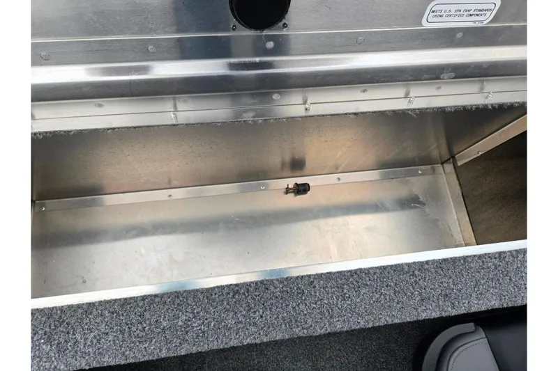 Slide: The Image of 2025 Tracker Pro 170 boat storage compartment with metallic interior and carpeted edges. - 22