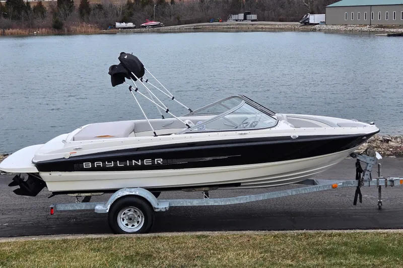 The Image of 2011 Bayliner 195 boat on trailer by a lake, ready for launch. - 0