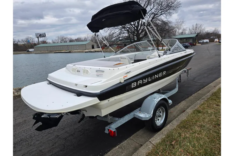 Slide: The Image of 2011 Bayliner 195 boat on trailer by waterfront, overcast sky. - 1