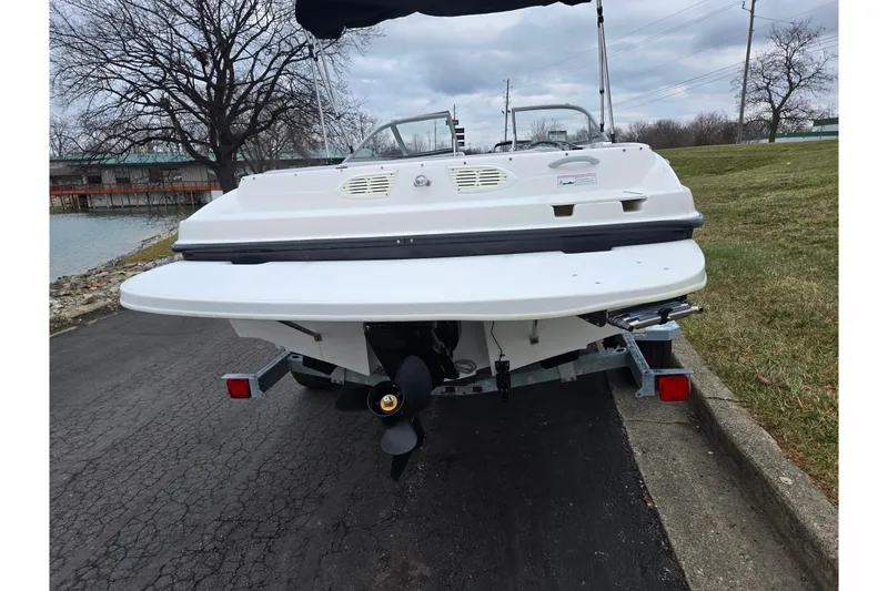 Slide: The Image of 2011 Bayliner 195 boat on trailer, rear view, near water and grassy area. - 2