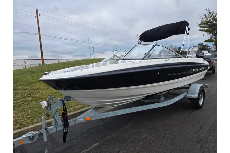 Slide: The Image of 2011 Bayliner 195 boat on trailer with black canopy, parked on paved road. - 5
