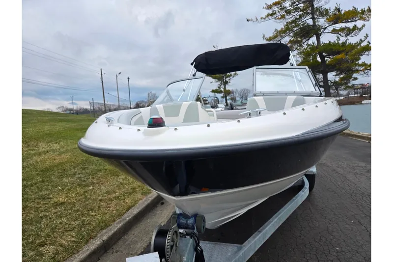 Slide: The Image of 2011 Bayliner 195 boat on trailer, parked near grassy area and water. - 6