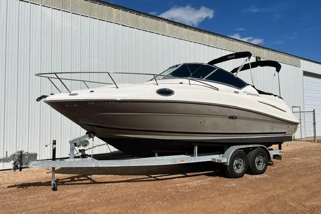 Slide: The Image of 2008 Sea Ray 240 Sundancer boat on trailer, parked outside a large white building. - 2