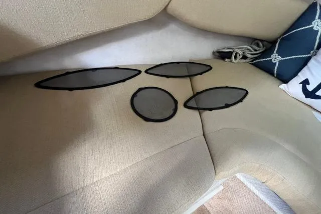 Slide: The Image of Interior of 2008 Sea Ray 240 Sundancer with oval speaker covers on beige seating. - 20