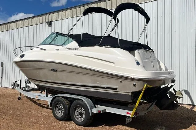 Slide: The Image of 2008 Sea Ray 240 Sundancer boat on trailer, parked outdoors near a metal building. - 3
