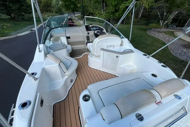 Slide: The Image of 2008 Sea Ray 240 Sundancer boat interior with seating and steering wheel, docked near greenery. - 8