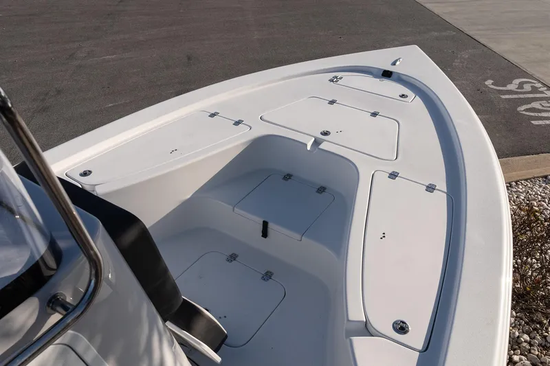 Slide: The Image of 2026 Sea Pro 230 Bay boat deck with storage compartments, shown in a parking area. - 13