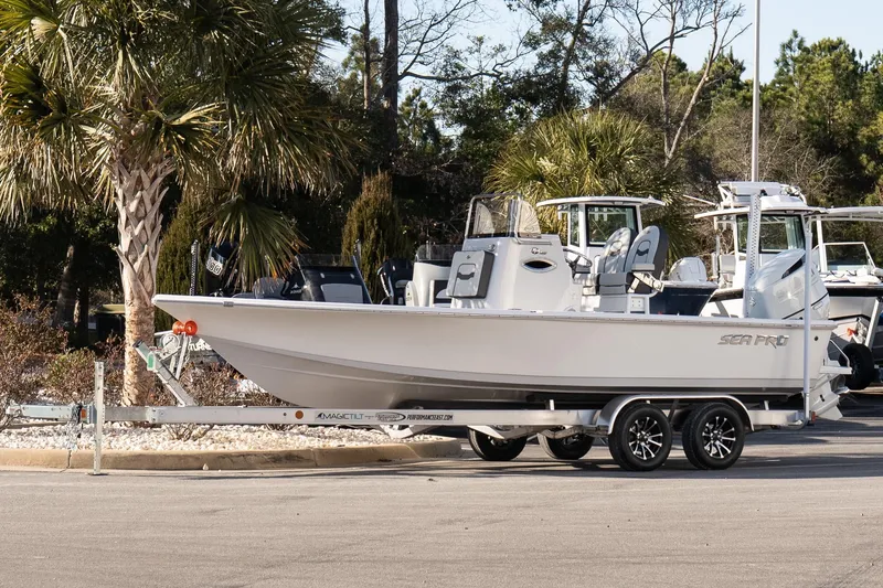 Slide: The Image of 2026 Sea Pro 230 Bay boat on trailer, parked near palm trees. - 2