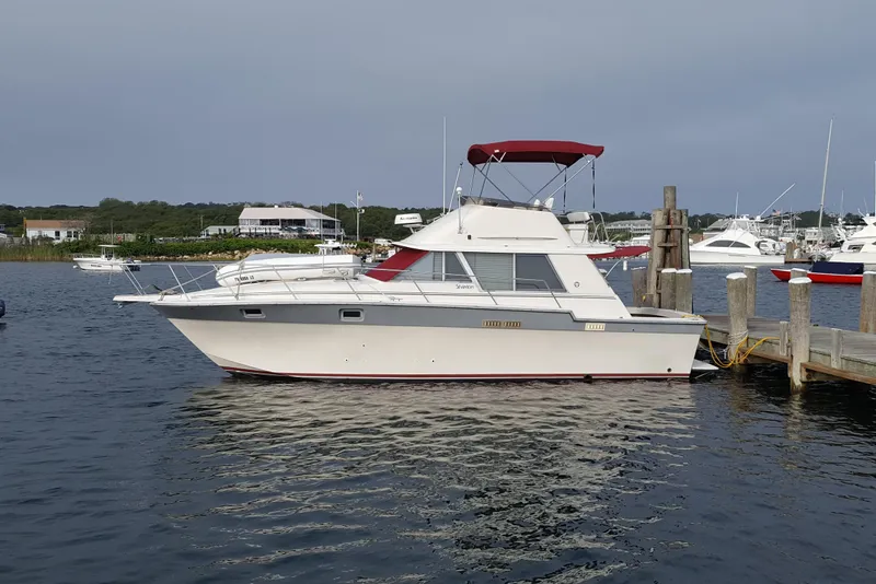 The Image of 1988 Silverton 34 Convertible yacht docked at a marina, featuring a red canopy. - 0