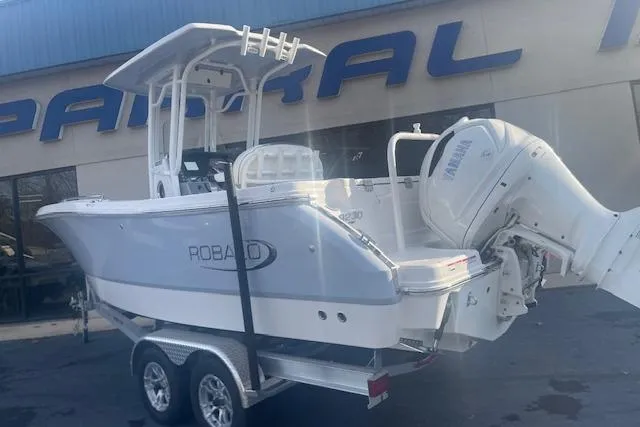 Slide: The Image of 2024 Robalo R230 Center Console boat on trailer, displayed outside dealership. - 2