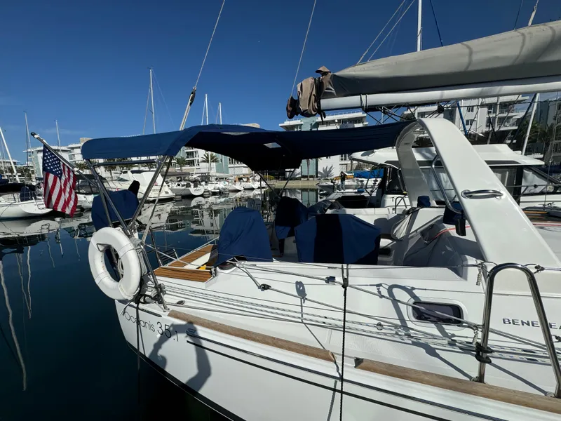 Slide: The Image of 2021 Beneteau Oceanis 35.1 sailboat docked in marina, featuring blue canopy and American flag. - 14