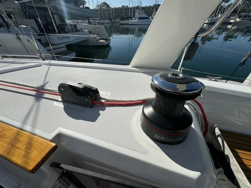 Slide: The Image of Beneteau Oceanis 35.1 sailboat deck with winch and red rope, docked in marina, 2021 model. - 31