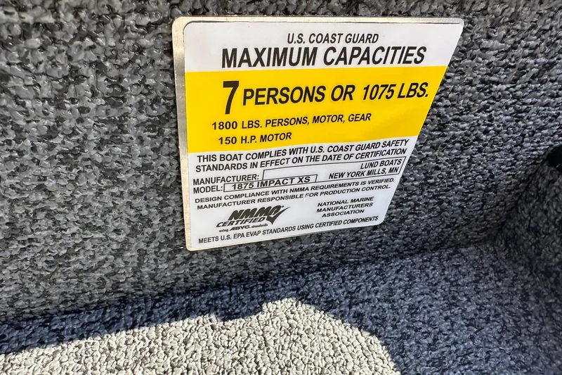 Slide: The Image of 2026 Lund 1875 Impact XS SS boat capacity label, 7 persons or 1075 lbs, U.S. Coast Guard compliant. - 27