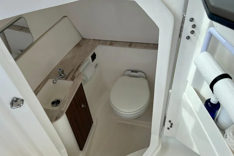 Slide: The Image of 2020 Pursuit DC 266 Dual Console boat bathroom with sink, toilet, and storage cabinet. - 15