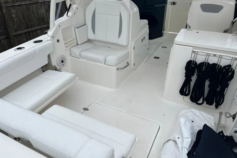 Slide: The Image of 2020 Pursuit DC 266 Dual Console boat interior with white seating and storage. - 19