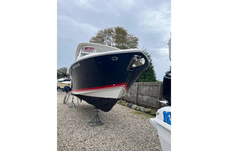Slide: The Image of 2020 Pursuit DC 266 Dual Console boat on stands, gravel yard, overcast sky. - 4