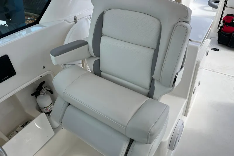 Slide: The Image of 2020 Pursuit DC 266 Dual Console boat seat with armrests and fire extinguisher nearby. - 6
