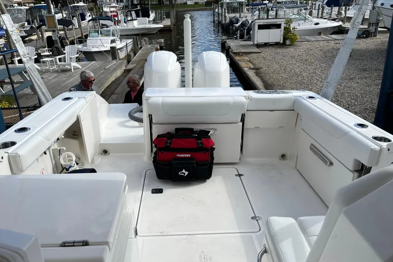 Slide: The Image of 2020 Pursuit DC 266 Dual Console boat interior at marina, featuring white seating and storage. - 7