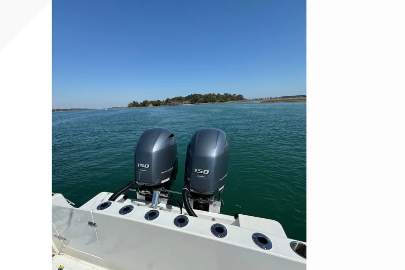 Slide: The Image of Twin outboard motors on a 1998 Contender 23 Open boat, cruising on clear blue water. - 5
