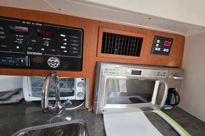 Slide: The Image of 2008 Everglades 350LX boat kitchen with control panel, microwave, and sink. - 28