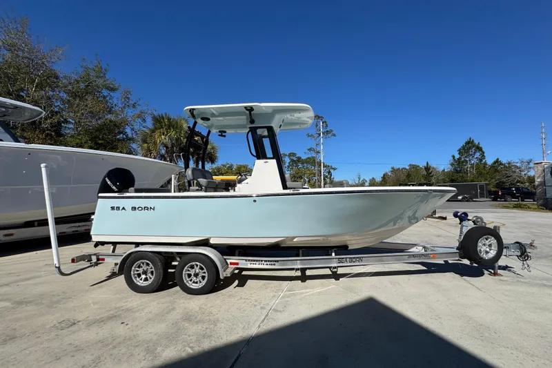 Slide: The Image of 2026 Sea Born LX22 Center Console boat on trailer, parked outdoors under clear blue sky. - 9