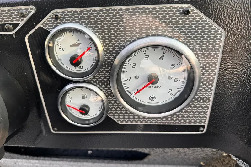 Slide: The Image of Dashboard gauges of 2026 Lund 1875 Impact XS Sport boat, featuring RPM, trim, and fuel indicators. - 16