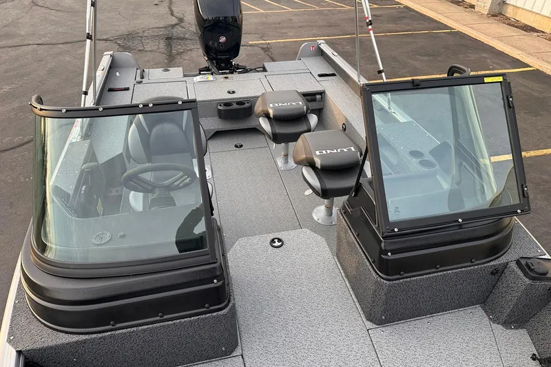 Slide: The Image of 2026 Lund 1875 Impact XS Sport boat with dual consoles and seating, parked on pavement. - 19