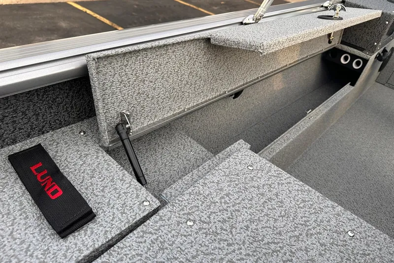Slide: The Image of 2026 Lund 1875 Impact XS Sport boat interior with storage compartments and carpeted finish. - 21