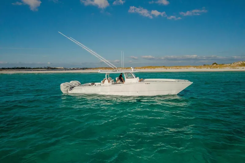 The Image of 2024 Freeman 47 boat cruising on clear turquoise waters near a sandy shoreline. - 1