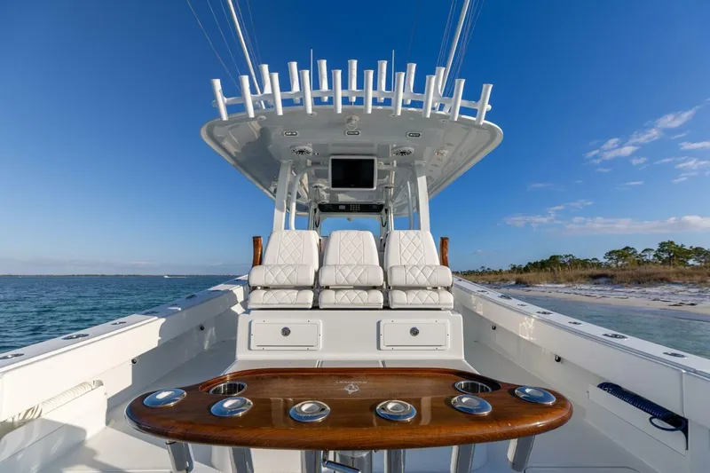 Slide: The Image of 2024 Freeman 47 boat interior with luxurious seating and fishing rod holders, ocean backdrop. - 13
