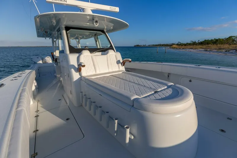 Slide: The Image of 2024 Freeman 47 boat with luxurious seating, cruising on calm waters near a sandy shoreline. - 23