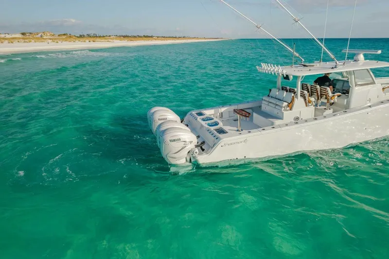 Slide: The Image of 2024 Freeman 47 boat cruising in clear turquoise waters near a sandy beach. - 33