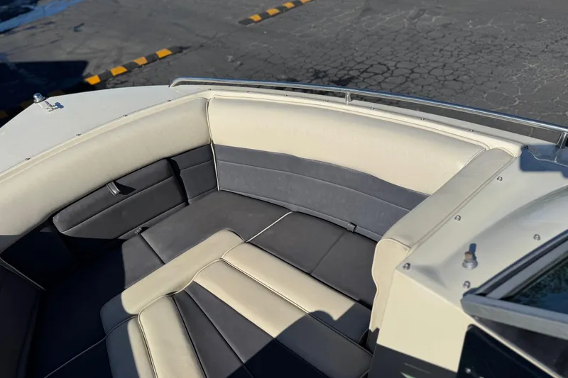 Slide: The Image of 1988 Cobalt 222 boat interior with beige and gray seating, docked on cracked pavement. - 12