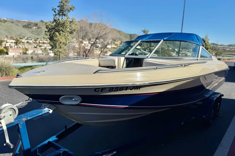Slide: The Image of 1988 Cobalt 222 boat on trailer, parked outdoors with scenic background. - 3