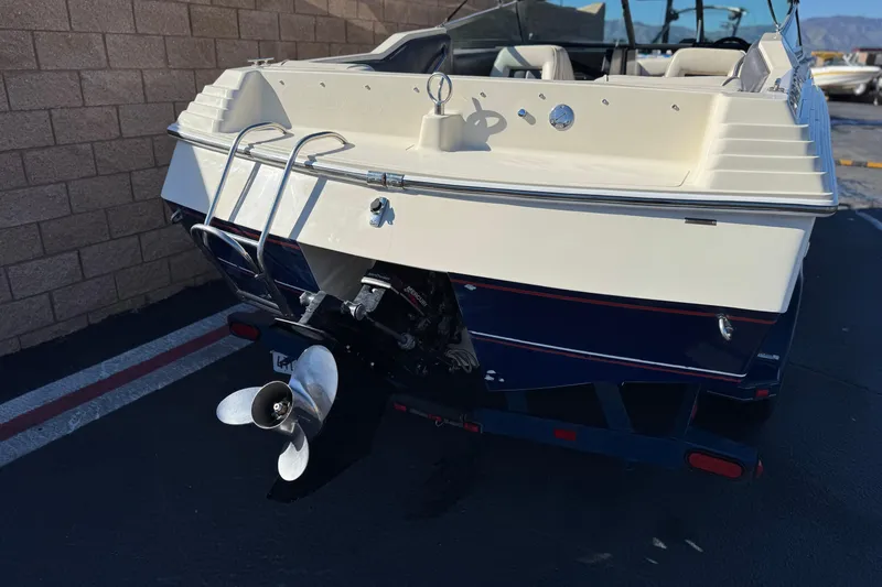 Slide: The Image of 1988 Cobalt 222 boat rear view with propeller and ladder, parked outdoors. - 6