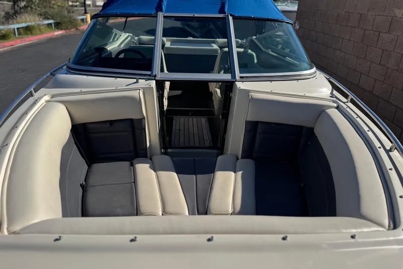 Slide: The Image of 1988 Cobalt 222 boat with blue canopy and beige seating, docked near a brick wall. - 9