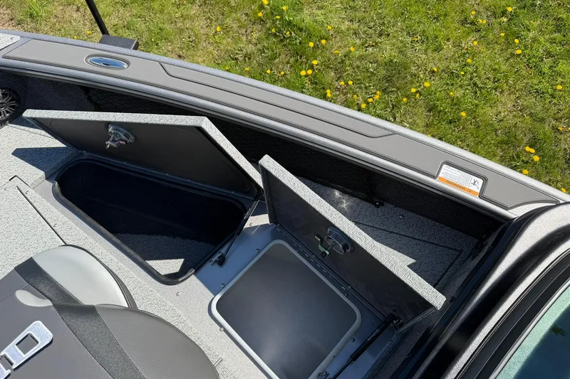 Slide: The Image of Open storage compartments on a 2026 Lund 1875 Pro-V boat, with grassy background. - 21