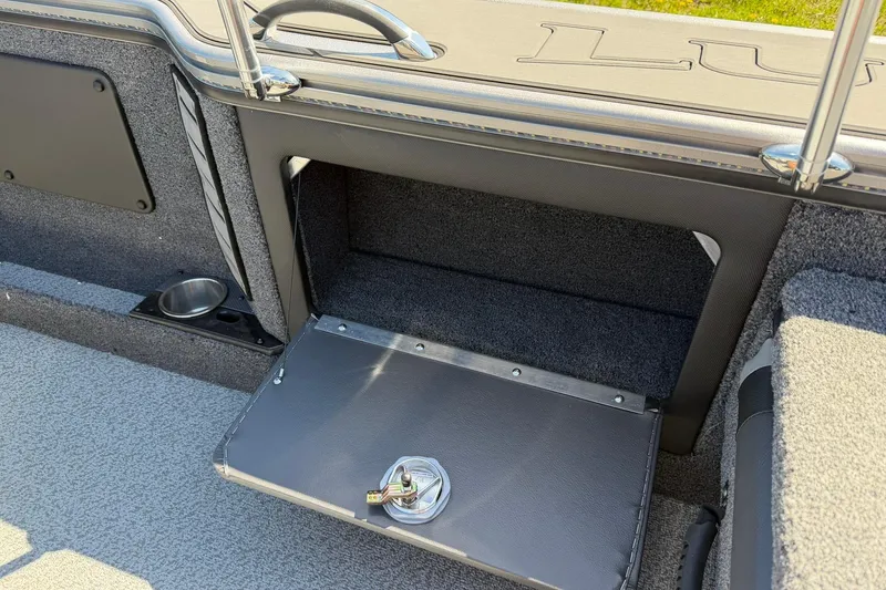 Slide: The Image of 2026 Lund 1875 Pro-V boat interior storage compartment with open hatch and cup holder. - 28