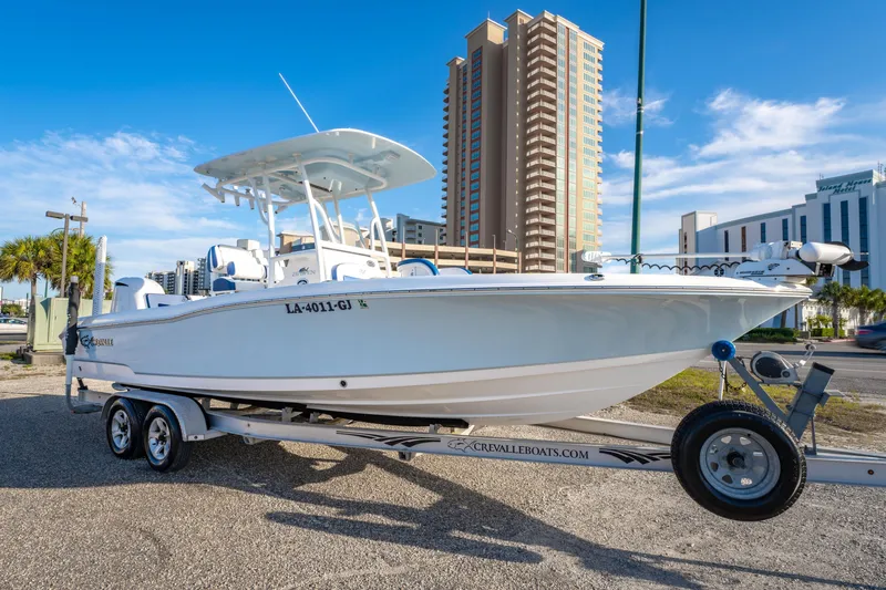 Slide: The Image of 2017 Crevalle 26 Open boat on trailer, urban backdrop, clear sky. - 2