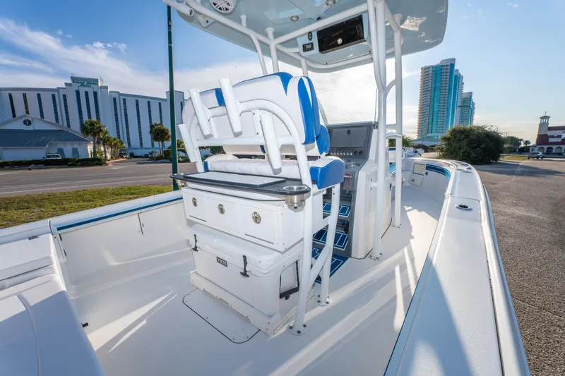 Slide: The Image of 2017 Crevalle 26 Open boat interior with blue and white seating, docked near buildings. - 33