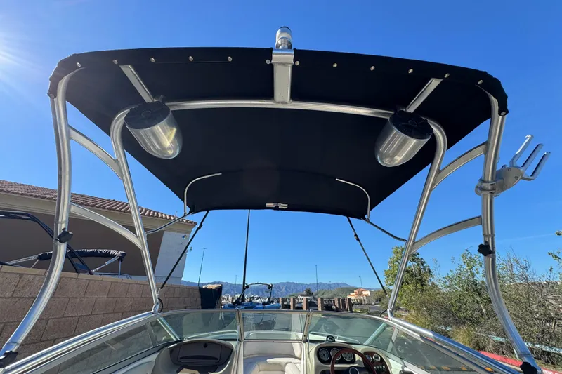 Slide: The Image of 2005 Chaparral 210 SSi boat with bimini top and speakers, sunny outdoor setting. - 10