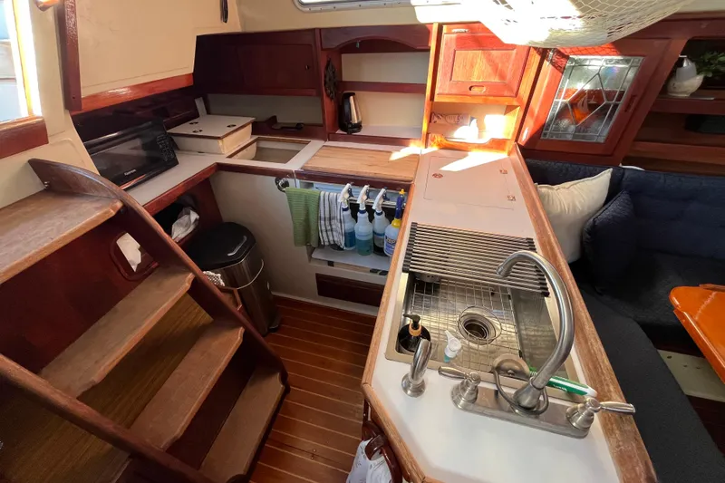 Slide: The Image of Interior of 1984 Catalina 36 MkII sailboat, featuring a compact kitchen with wooden cabinetry. - 24