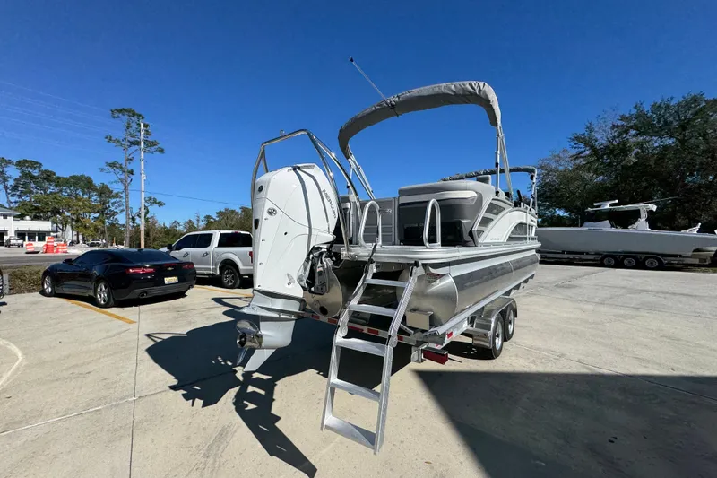 Slide: The Image of 2026 Bennington 23 MFB pontoon boat on trailer, parked outdoors under clear blue sky. - 14