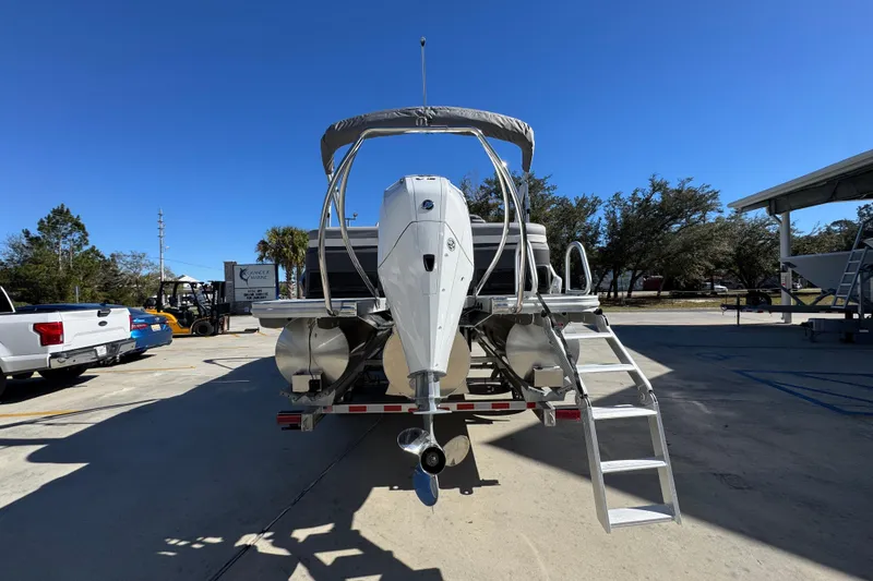 Slide: The Image of 2026 Bennington 23 MFB boat on trailer with outboard motor and ladder, parked outdoors. - 15