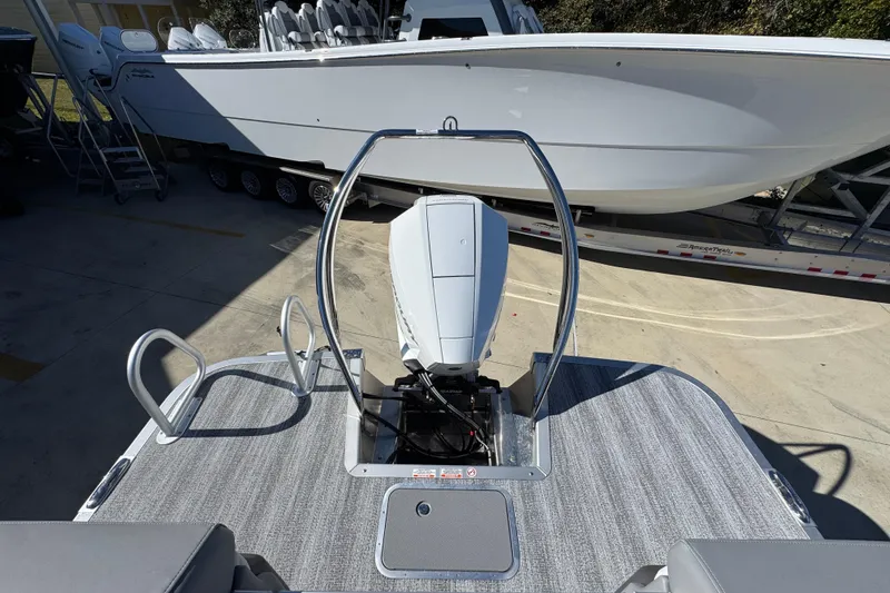 Slide: The Image of 2026 Bennington 23 MFB boat with outboard motor, docked beside a larger vessel. - 34