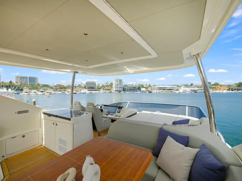 Slide: The Image of 2024 Absolute 60 Fly yacht flybridge with seating, table, and marina view. - 11