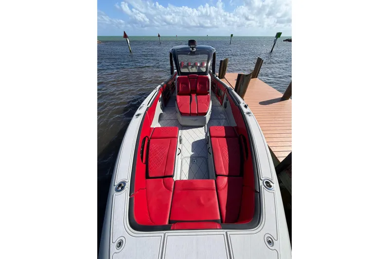 Slide: The Image of 2020 Deep Impact 399 Sport boat with red seating, docked by the water. - 5