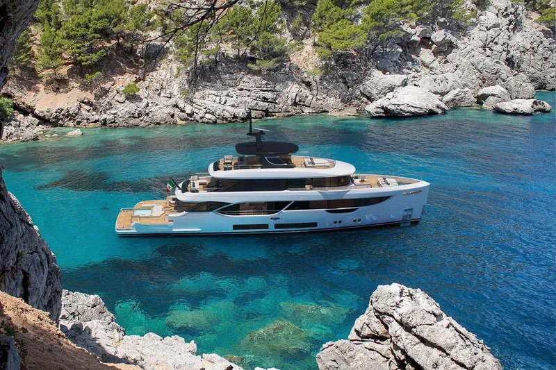 Slide: The Image of Luxurious 2023 Benetti Oasis 34M yacht in a serene, rocky coastal setting. - 32