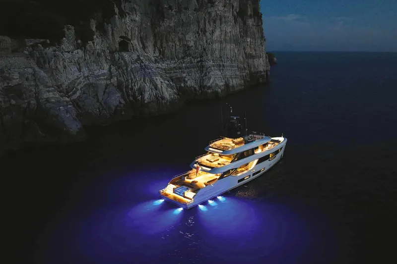 Slide: The Image of 2023 Benetti Oasis 34M yacht illuminated at night near rocky cliffs. - 35